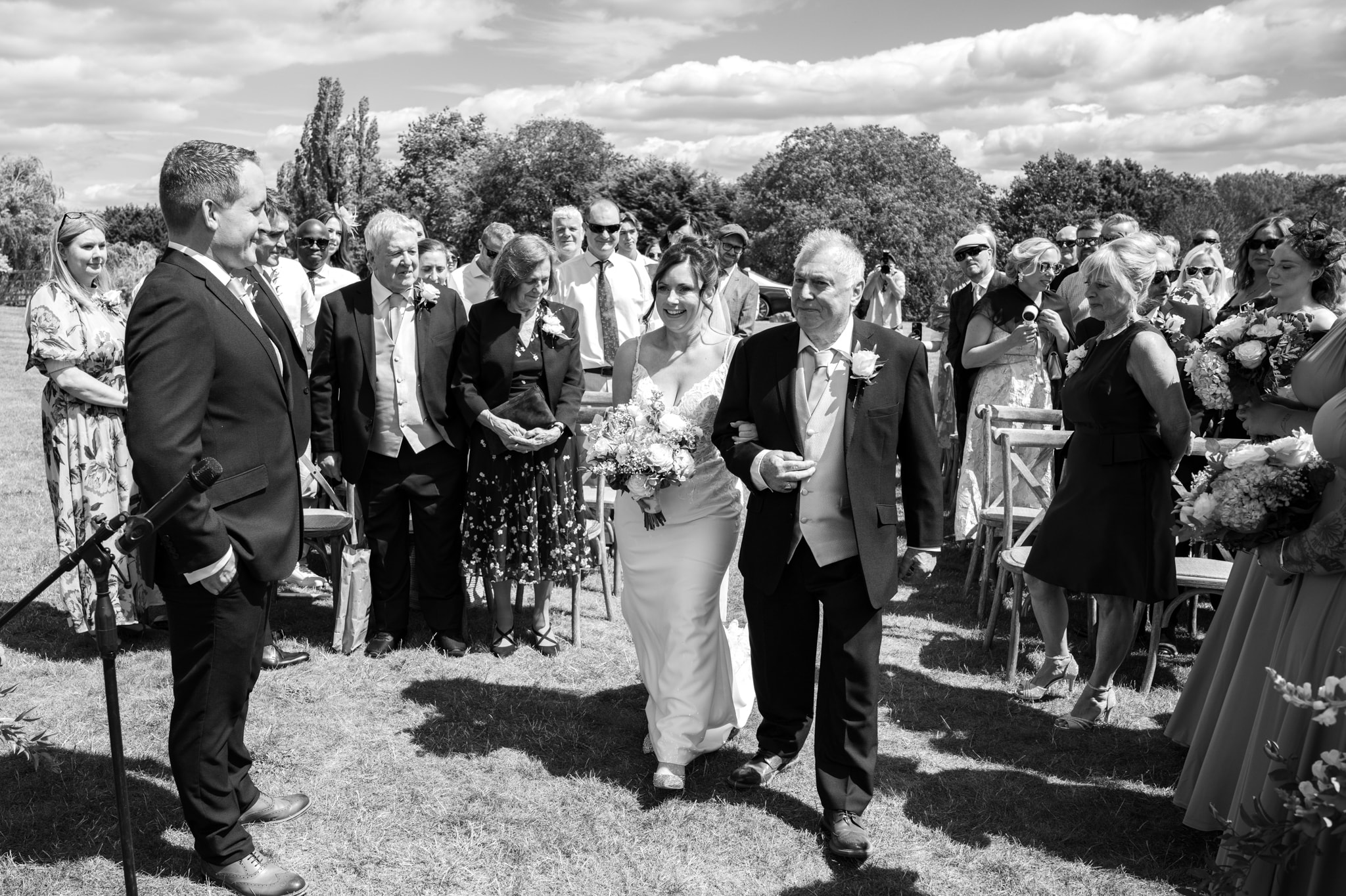 Bride walking down the aisle with father at Notley Tythe Barn outdoor ceremony