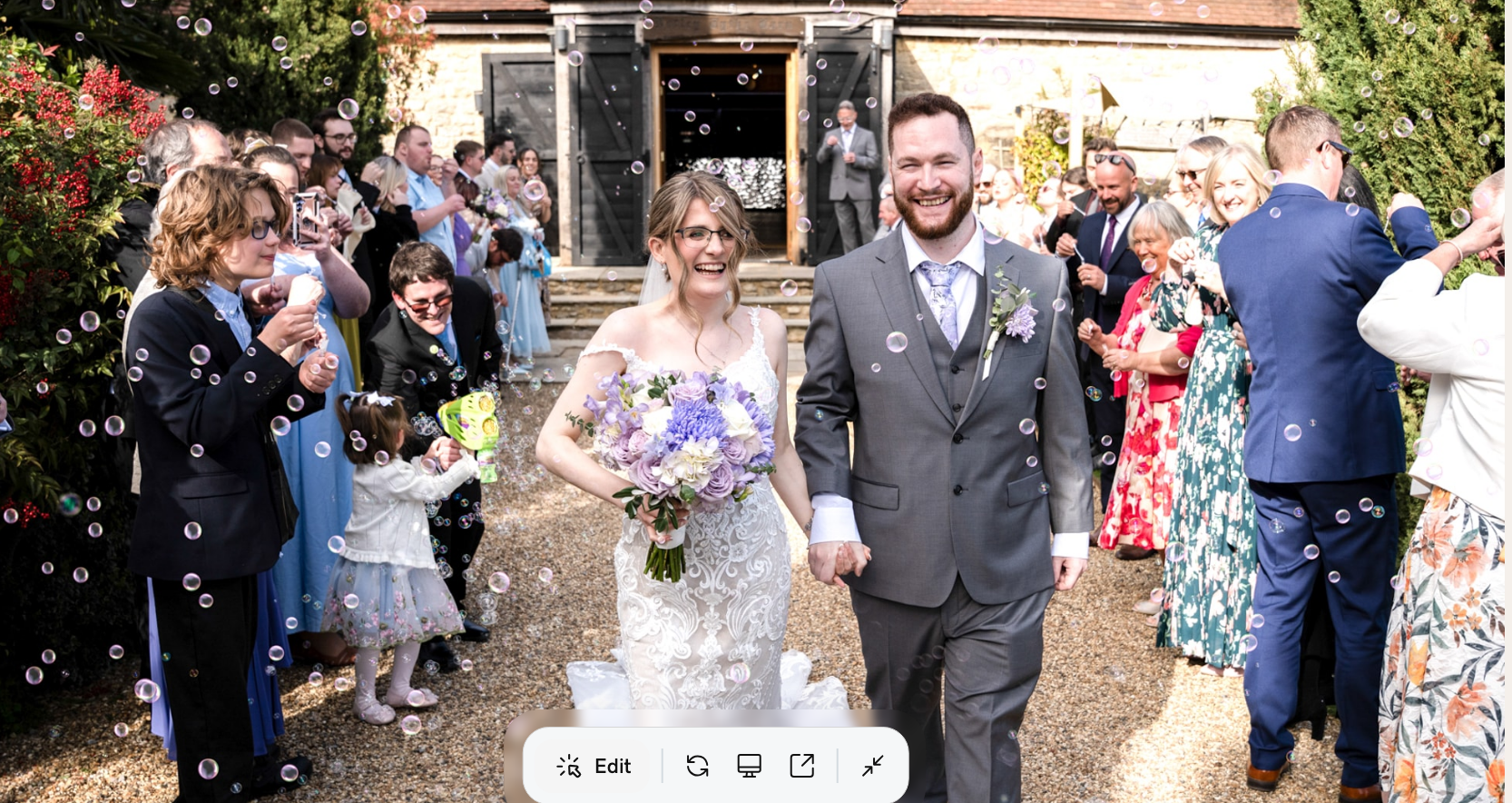 Bride and groom walking through bubble exit with guests cheering outside Notley Tythe Barn