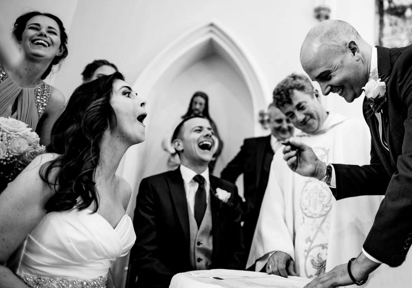 Bride and groom and wedding guests laughing black and white image