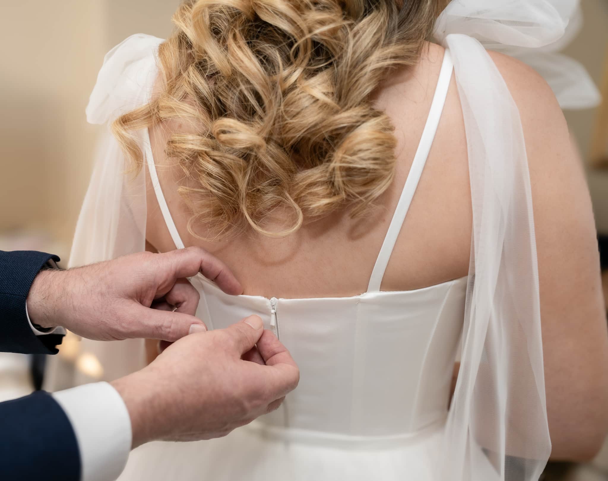 white wedding drss being zipped up