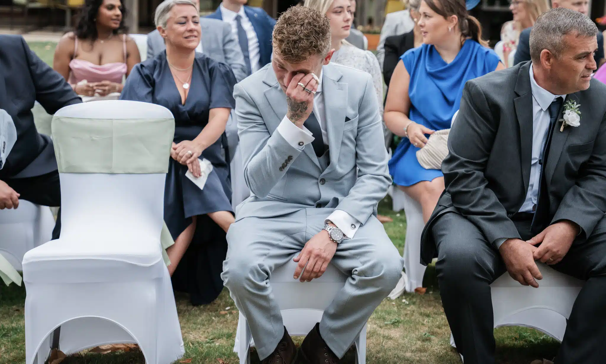 man in pale blue suit crying at wedding