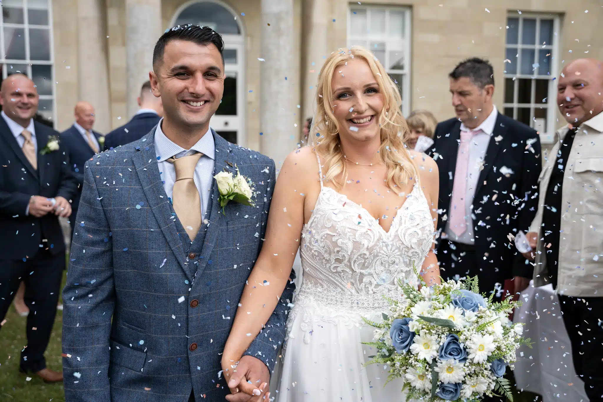 bride and groom under a shower of white confetti at The Hitchin Priory