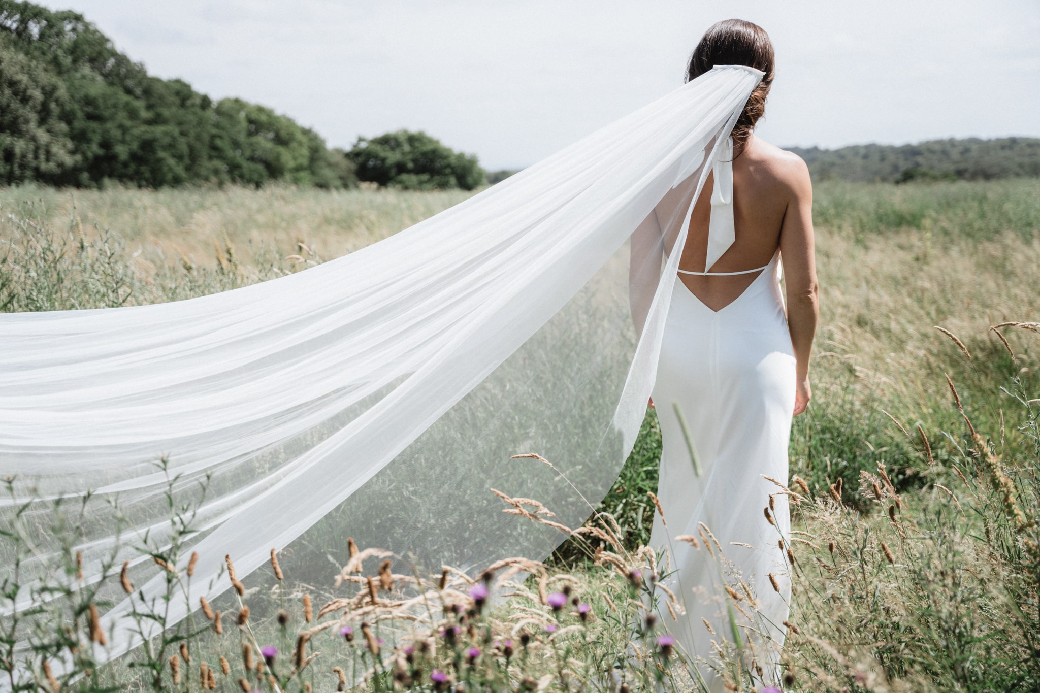 bride in field with long white veil